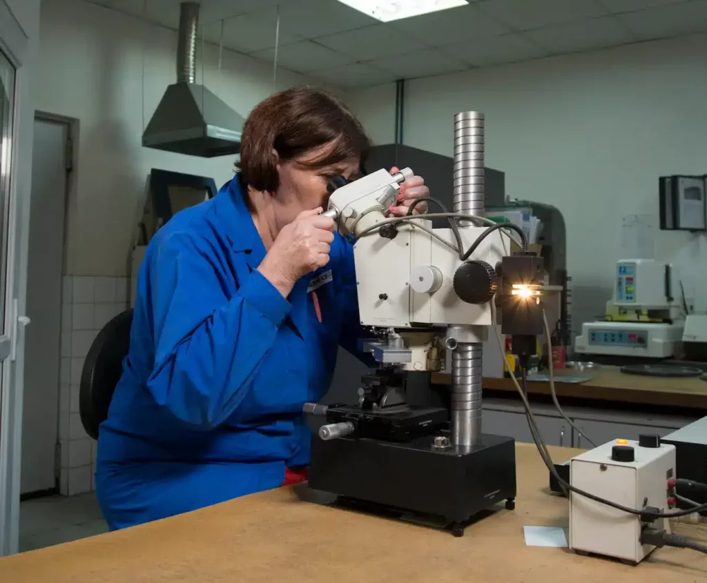 femme controlant au microscope une pièce traitée